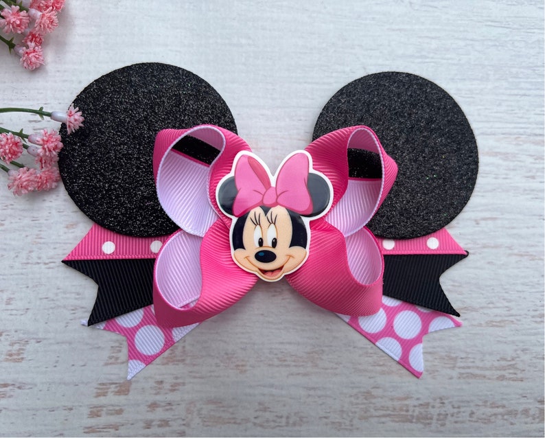 May include: Pink and black Minnie Mouse hair bow with black glitter ears and white polka dot accents.