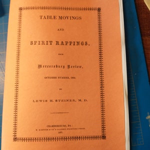 May include: A vintage book cover with an orange background and black text. The title is "Table Movings and Spirit Rappings" from the "Mercersburg Review" October 1861. The author is Lewis H. Steiner, M.D.