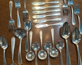 May include: A set of silverware, including forks, spoons, and butter knives, all made of polished silver. The silverware is arranged on a wooden table.