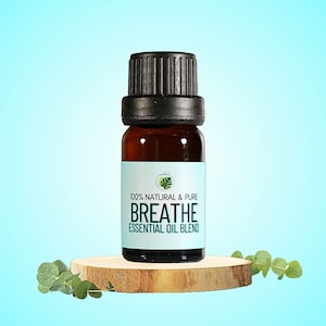 May include: A brown glass bottle with a black lid, containing essential oil. The bottle is labeled "100% NATURAL & PURE BREATHE ESSENTIAL OIL BLEND". The bottle is sitting on a wooden round platform.