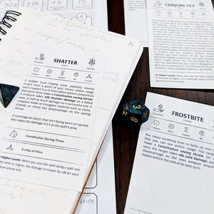 May include: A close-up of a Dungeons and Dragons rulebook open to the Shatter spell description. The spell description includes the spell's name, a description of the spell's effects, and the Constitution saving throw required to resist the spell's effects. The image also includes a few dice, including a blue and green d6 die.