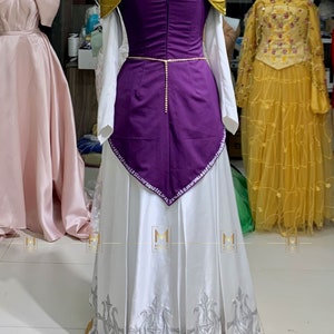 May include: A white and purple princess costume with gold accents. The dress has a white skirt with a gold trim and a purple bodice with gold shoulder pads. The bodice is decorated with rhinestones.