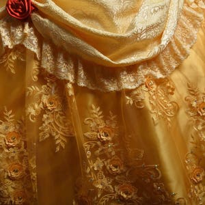 May include: A yellow satin and lace dress with a ruffled neckline and a floral pattern. The dress has a fitted bodice and a full skirt.