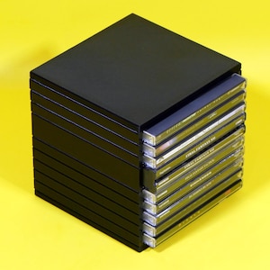 May include: A black plastic storage tower containing nine stacked video game cases. The spines of the cases are visible, displaying titles such as Final Fantasy VII, Final Fantasy Tactics, Einhander, Bushido Blade, and Diablo in white text.