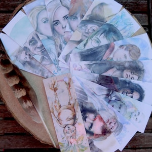 Puede incluir: Un conjunto de marcadores de libros de acuarela con personajes de la serie Harry Potter. Los marcadores están pintados en tonos de azul, verde y marrón. Los personajes incluyen a Harry Potter, Ron Weasley, Hermione Granger, Dobby el elfo doméstico y el Sauce Boxeador.