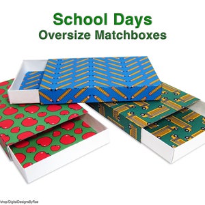 May include: Three oversized matchboxes with different designs. The first box has a blue background with yellow pencils, the second box has a green background with yellow school buses, and the third box has a green background with red apples. The boxes are all open and the inside is white.