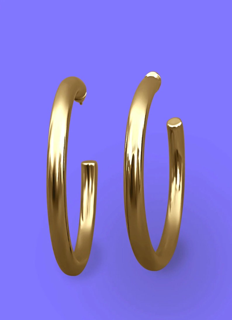 May include: A pair of gold hoop earrings. The earrings are thick and have a smooth, polished finish.