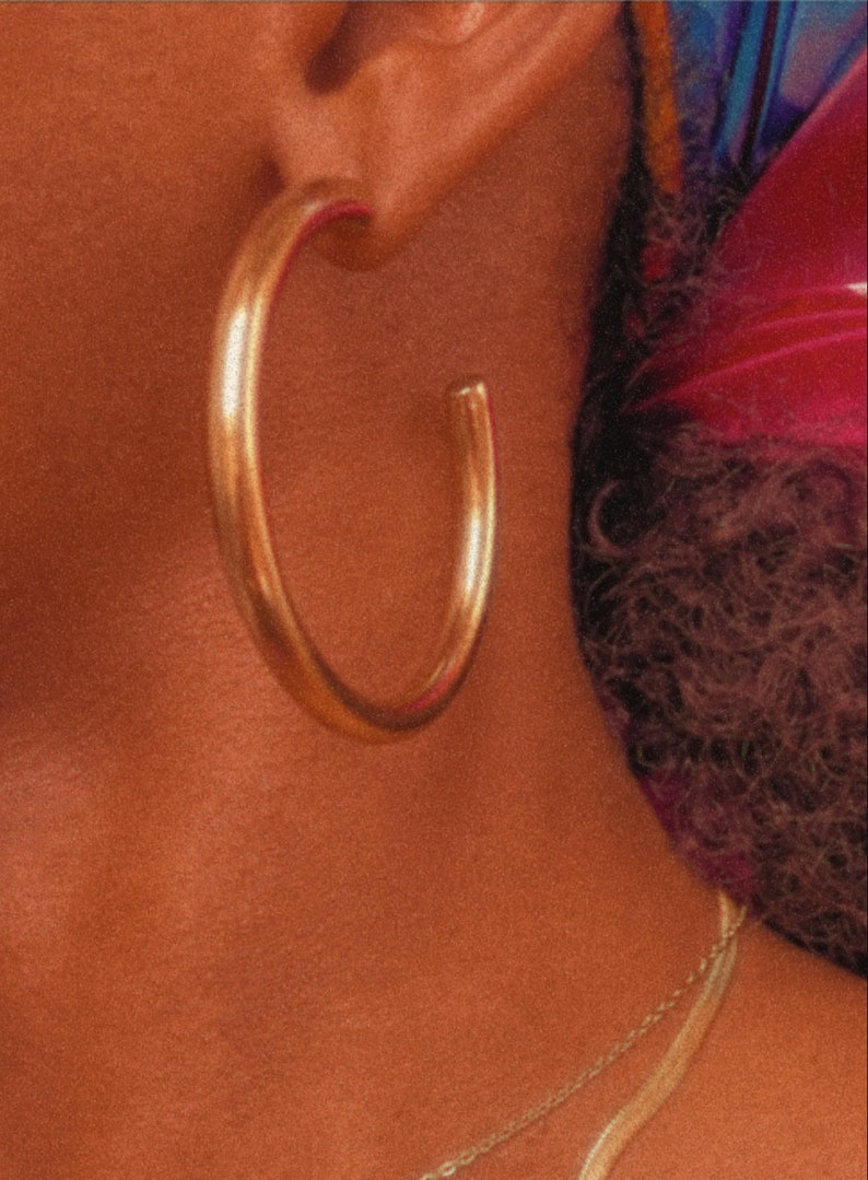 May include: A pair of large, gold hoop earrings. The earrings are thick and have a smooth, polished finish.