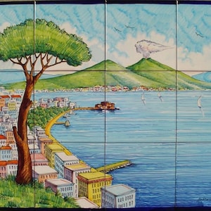 May include: A colorful ceramic tile mural depicting a view of a city with a volcano in the background. The city is on a bay with sailboats in the water. A green tree is in the foreground.