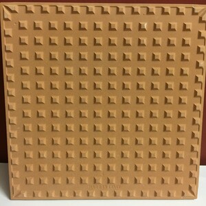 May include: A brown ceramic tile with a textured surface and the words "Made in Italy" printed on the bottom.