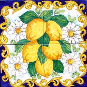 May include: A hand-painted ceramic tile featuring a cluster of yellow lemons with green leaves and white daisies. The tile has a blue and gold border.