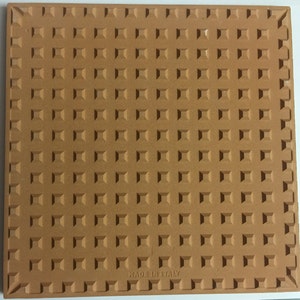 May include: A terracotta tile with a textured surface and the words "Made in Italy" printed on the bottom.