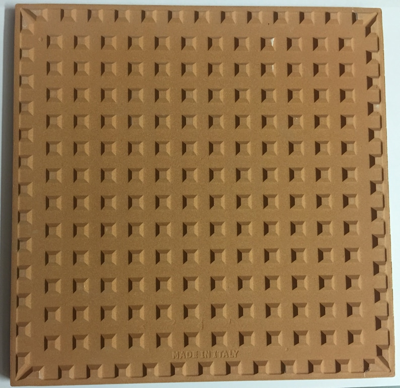 May include: A terracotta tile with a textured surface and the words "Made in Italy" printed on the bottom.
