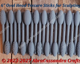 May include: A set of gray sculpting tools with oval heads featuring various textures, each 6 inches long as shown by the yellow measuring tape. The sticks are labeled AbraCassandra Crafts and the text 6" Oval Head Texture Sticks for Sculpting is visible.