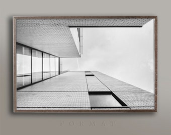 May include: Black and white photograph of a modern building with a brick exterior and large windows. The photo is taken from a low angle, looking up at the building.
