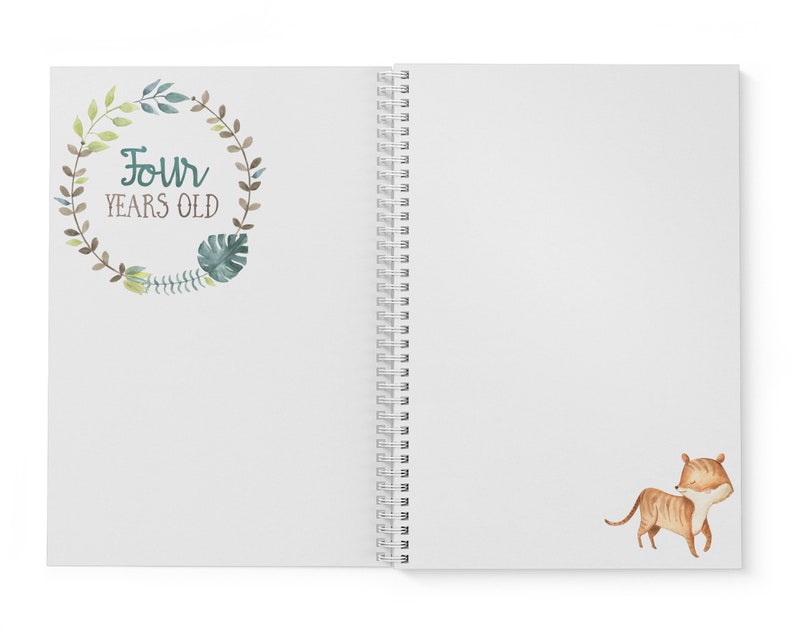 Puede incluir: Un cuaderno blanco de espiral con una corona de hojas verdes y marrones en la portada. La corona tiene el texto "Four Years Old" en su interior. La contraportada tiene una ilustraci&oacute;n de acuarela de un cachorro de tigre marr&oacute;n y naranja.