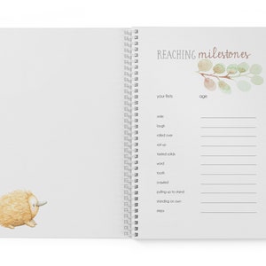 May include: A white spiral bound book with a watercolor illustration of a leafy branch on the cover. The book is titled "REACHING milestones" and has a section for recording a baby's firsts, such as their first smile, laugh, and steps.