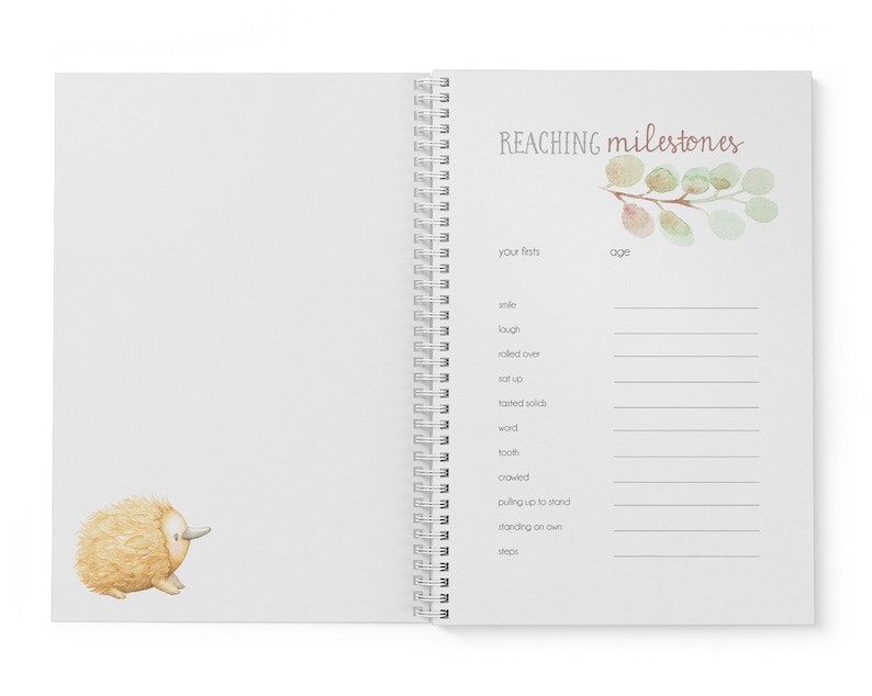 May include: A white spiral bound book with a watercolor illustration of a leafy branch on the cover. The book is titled "REACHING milestones" and has a section for recording a baby's firsts, such as their first smile, laugh, and steps.