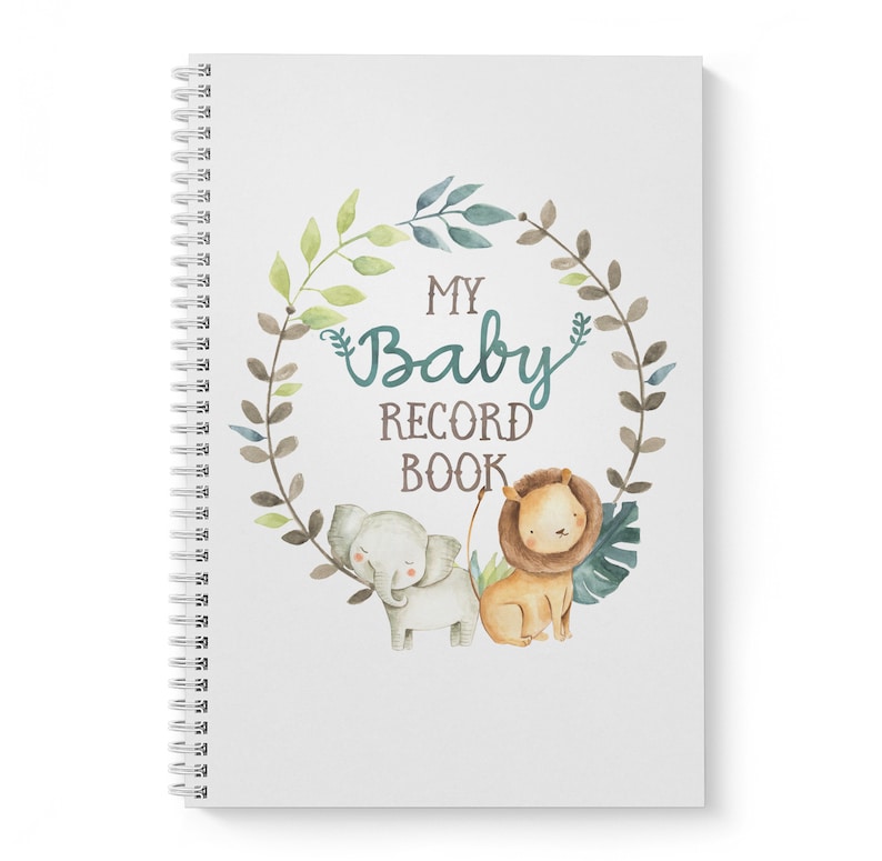 Puede incluir: Una libreta blanca de espiral con una ilustraci&oacute;n de acuarela de una corona de hojas con un elefante y un le&oacute;n. El texto "My Baby Record Book" est&aacute; en el centro de la corona.