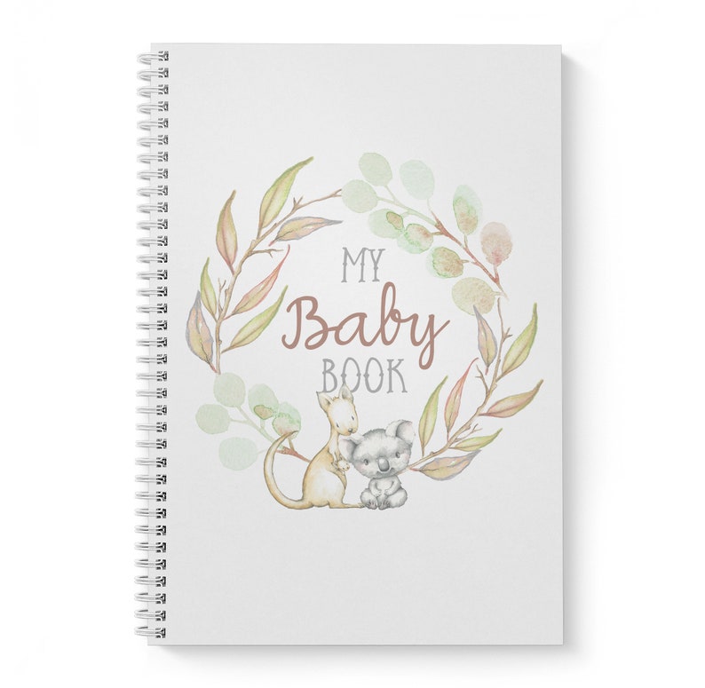 May include: A white baby book with a watercolor wreath of leaves and flowers. The text "My Baby Book" is in the center of the wreath. A kangaroo and a koala are inside the wreath.