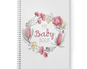 Può includere: Un diario bianco a spirale con una ghirlanda ad acquerello di fiori rosa e rossi e foglie verdi. Il testo "My Baby Book" è al centro della ghirlanda.
