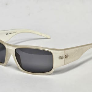 May include: Sunglasses with a translucent off-white frame and dark gray lenses. The inner temple arm features the text SOLIZE. The design includes a wrap-around style frame with integrated hinges and curved arms for a secure fit over the ears.