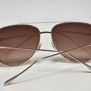 Puede incluir: Gafas de sol estilo aviador con montura de metal dorado y lentes degradadas marrones. Las finas patillas se extienden hacia atr&aacute;s, con "DIFF" visible en la patilla izquierda. El n&uacute;mero "1110" est&aacute; en la barra superior.