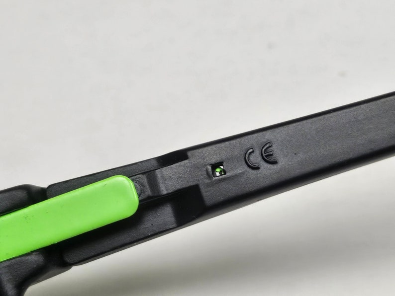 May include: Close-up of a black and green pair of glasses with a CE marking on the side.