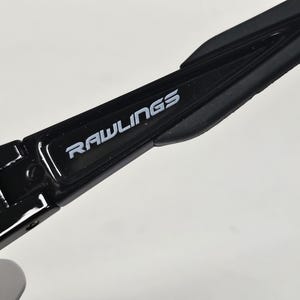 K&ouml;nnte beinhalten: Nahaufnahme eines schwarzen Sportbrillenb&uuml;gels mit dem Markennamen "RAWLINGS" in wei&szlig;er Schrift. Der B&uuml;gel hat eine gl&auml;nzende Oberfl&auml;che und ein strukturiertes Design.
