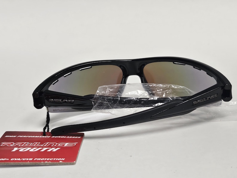 K&ouml;nnte beinhalten: Schwarze Rawlings Youth Sonnenbrille mit verspiegelten Gl&auml;sern. Die Sonnenbrille hat ein sportliches Design und ist neu mit Etikett. Das Etikett lautet "Rawlings Youth" und "High Performance Sunglasses".