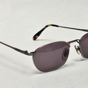 May include: Silver-toned metal sunglasses with brown tortoise shell temple tips and dark gray lenses.
