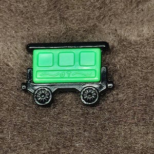 Puede incluir: Un vagón de tren verde con ruedas negras y techo negro. El vagón tiene tres ventanas y el texto "d.t." en el lateral.