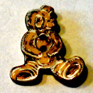 Könnte beinhalten: Eine braune und weiße Keramikfigur eines Teddybären, der einen kleineren Teddybären hält. Die Figur steht auf einer weißen Oberfläche.