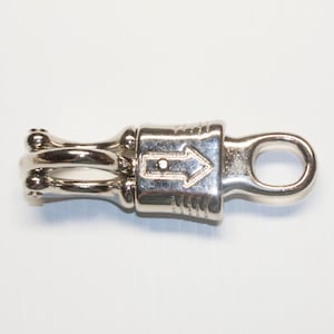 May include: Silver-toned metal clasp with a double loop on one end and a single loop on the other. An arrow is engraved on the clasp.