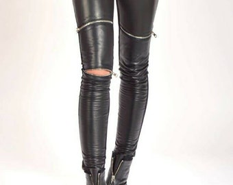 May include: Black leather leggings with zipper details and a distressed look. The leggings are worn with black ankle boots.