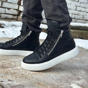 May include: Black leather high-top trainers with white soles and a zip detail on the side.