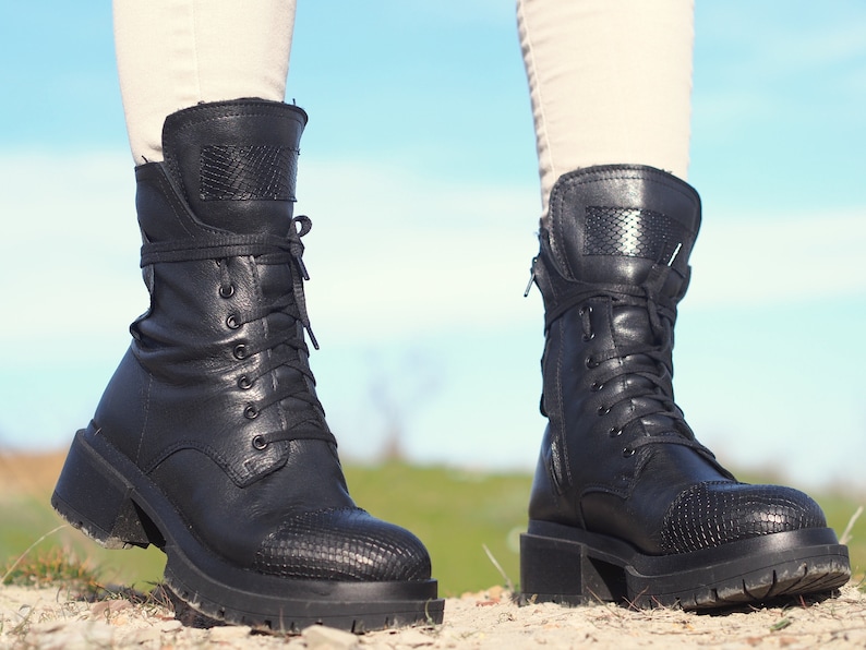 K&ouml;nnte beinhalten: Schwarze Lederstiefel mit Schn&uuml;rung, einem dicken Absatz und einem Rei&szlig;verschluss an der Seite.