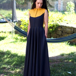 May include: A sleeveless maxi dress with a yellow collar and a black skirt. The dress has a fitted bodice and a flowing skirt.