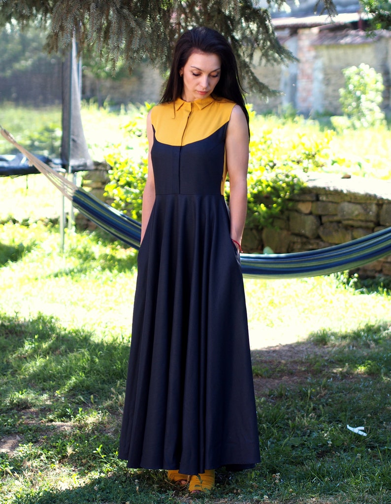 May include: A sleeveless maxi dress with a yellow collar and a black skirt. The dress has a fitted bodice and a flowing skirt.