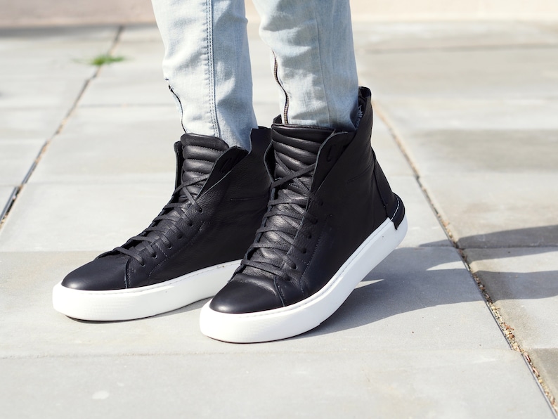 May include: Black high-top sneakers with white soles. The sneakers have a zipper on the side and a quilted design on the back.