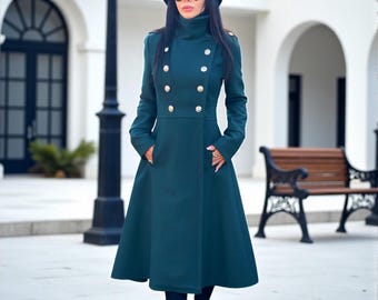 May include: A dark teal, knee-length, double-breasted coat featuring a high collar, long sleeves, and metallic buttons. The coat has a fitted bodice that flares at the waist, two side pockets, and is worn with a black hat and black boots.