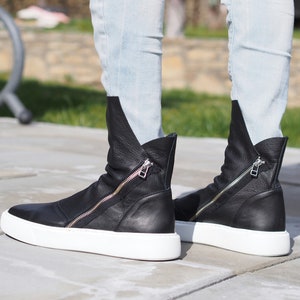 Puede incluir: Botas de tobillo de cuero negro con cremallera lateral y suela de plataforma blanca.