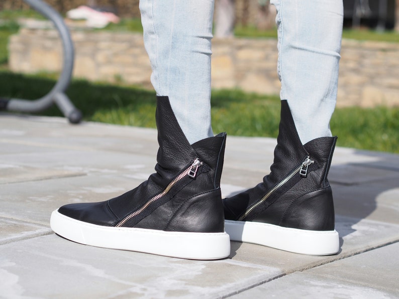 Puede incluir: Botas de tobillo de cuero negro con cremallera lateral y suela de plataforma blanca.