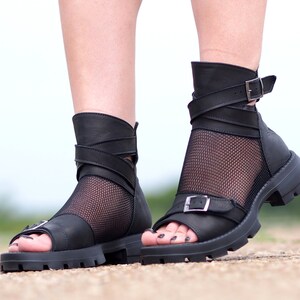 K&ouml;nnte beinhalten: Schwarze Ledersandalen mit einem Mesh-Einsatz und Schnallenverschl&uuml;ssen. Die Sandalen haben eine dicke Plateau-Sohle.