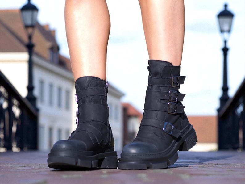 May include: Black ankle boots with a chunky sole and multiple buckle straps. The boots have a rugged, edgy design, perfect for adding a bold statement to any outfit. The boots are made of a durable material and feature a zipper closure.