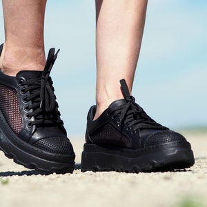 May include: A pair of black platform sneakers with mesh panels and black laces. The sneakers have a chunky sole.