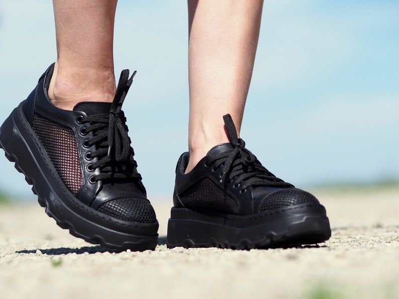 May include: A pair of black platform sneakers with mesh panels and black laces. The sneakers have a chunky sole.