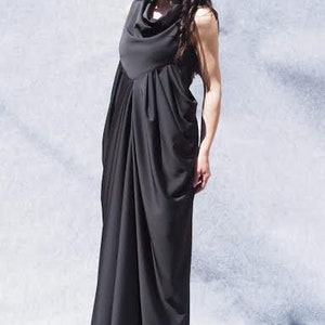 May include: A black maxi dress with a cowl neck and a draped design. The dress is made of a soft, flowing fabric.