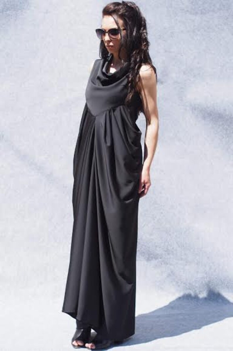May include: A black maxi dress with a cowl neck and a draped design. The dress is made of a soft, flowing fabric.