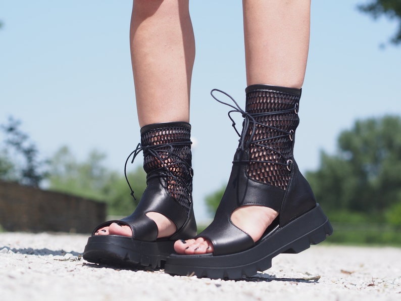 May include: Black leather platform sandals with a mesh upper and lace-up closure. The sandals have a chunky platform sole and an open toe design.